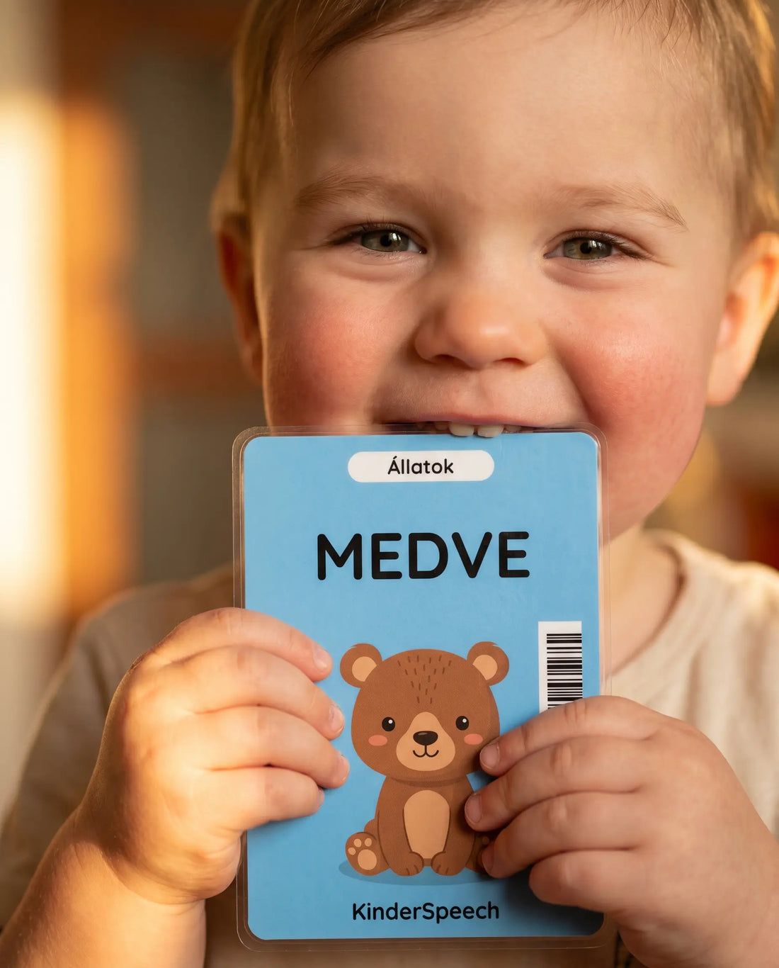 Mosolygós kisfiú kezében a Kinderspeech Medve szókártyával a kezében